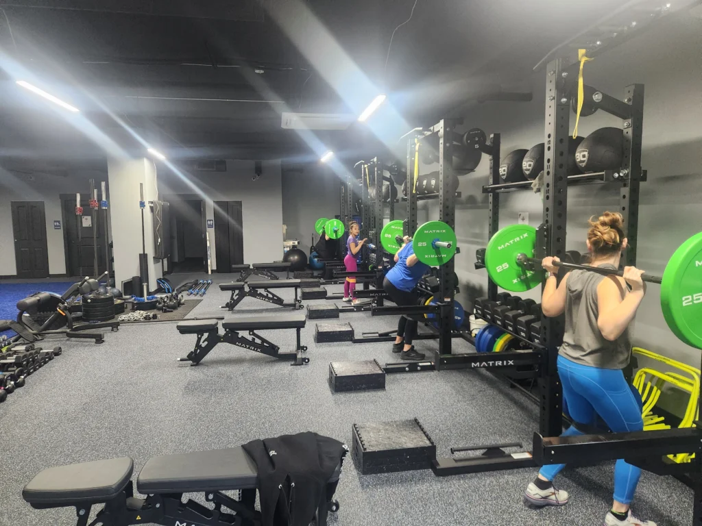 Clients performing barbell squats in the new Sound Sports training facility
