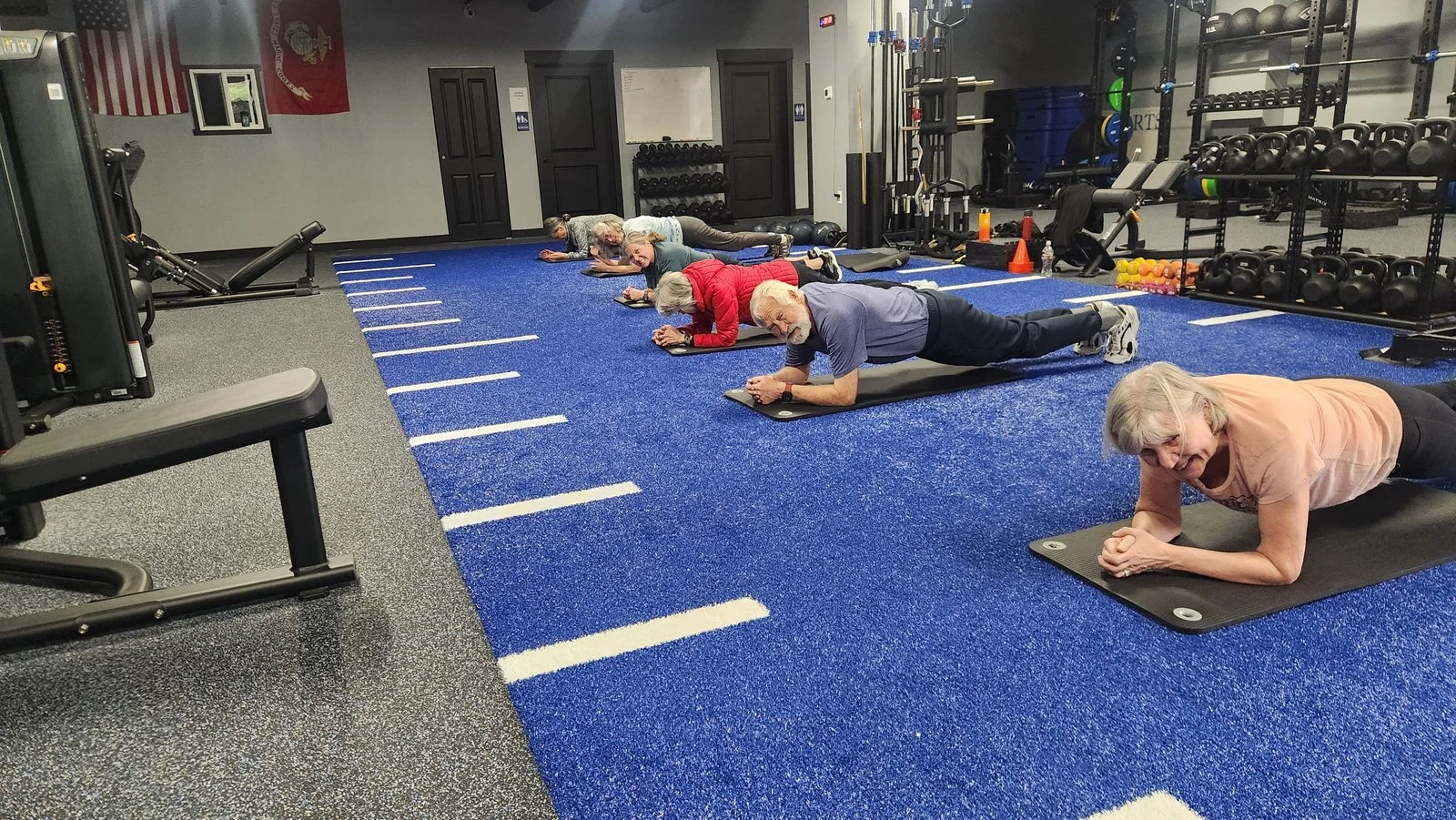 Group performing planks on blue turf at Sound Sports Performance and Training.